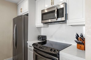 A modern kitchen with stainless steel appliances, including a refrigerator, microwave, and oven.