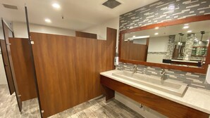 A modern bathroom with a wooden vanity, a large mirror, and a tiled backsplash.