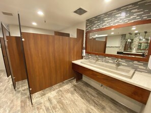Une salle de bain moderne avec un meuble-lavabo en bois, un grand miroir et un pare-feu en carreaux.