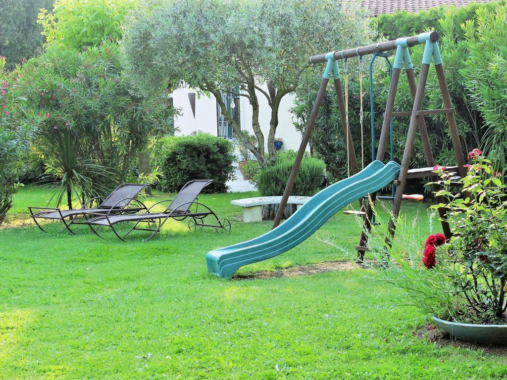 A backyard with a swing set, a slide, and two lounge chairs.