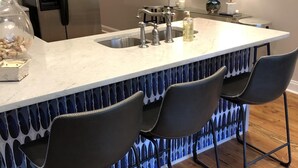 Moderni keittiö, jossa on keskeinen saareke, baarituoleja, jääkaappi ja seinällä McDonald’sin kyltti.