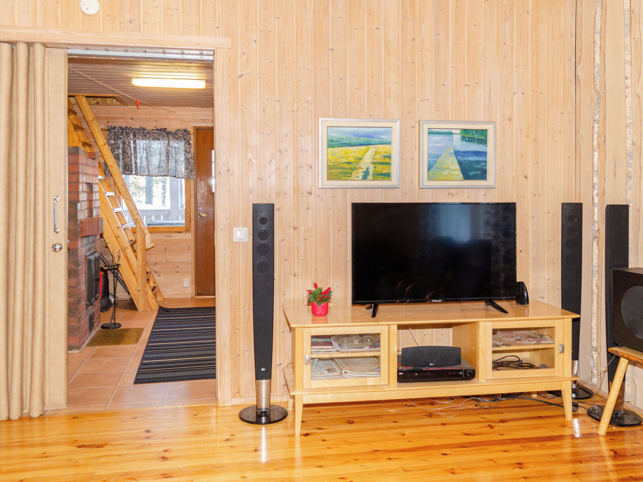 Um quarto com painéis de madeira, televisão, lareira e escada que leva a um andar superior.