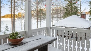 A wooden bench and table covered in snow, a potted plant, and a white picket fence.