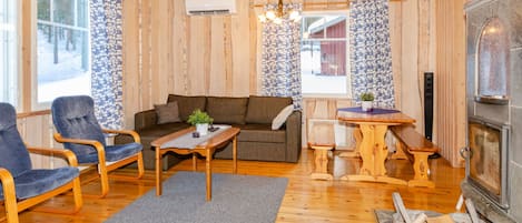 A cozy wooden interior with a sofa, chairs, a table, and a fireplace.