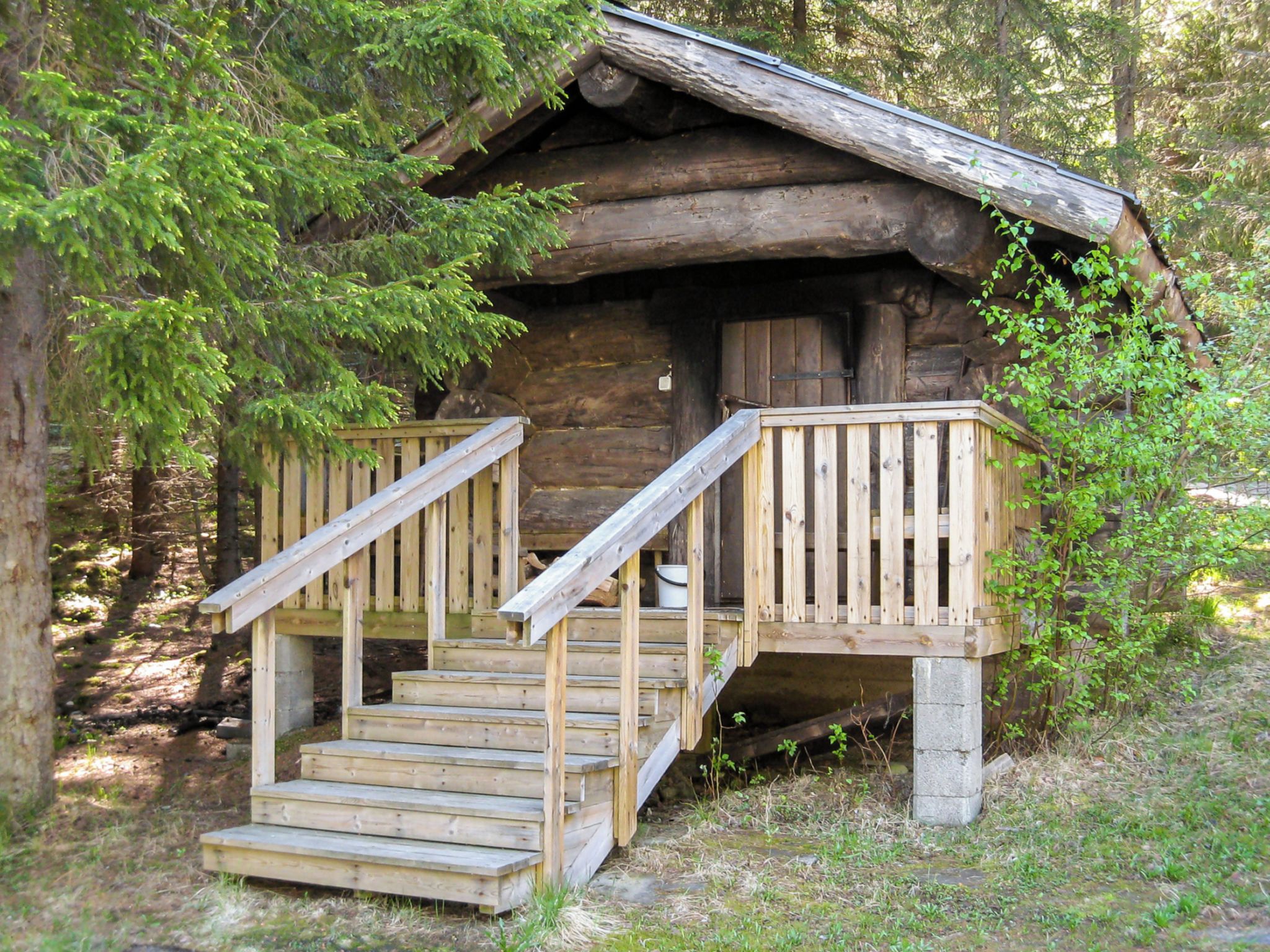 A rustic cabin with a wooden staircase leading to a deck.