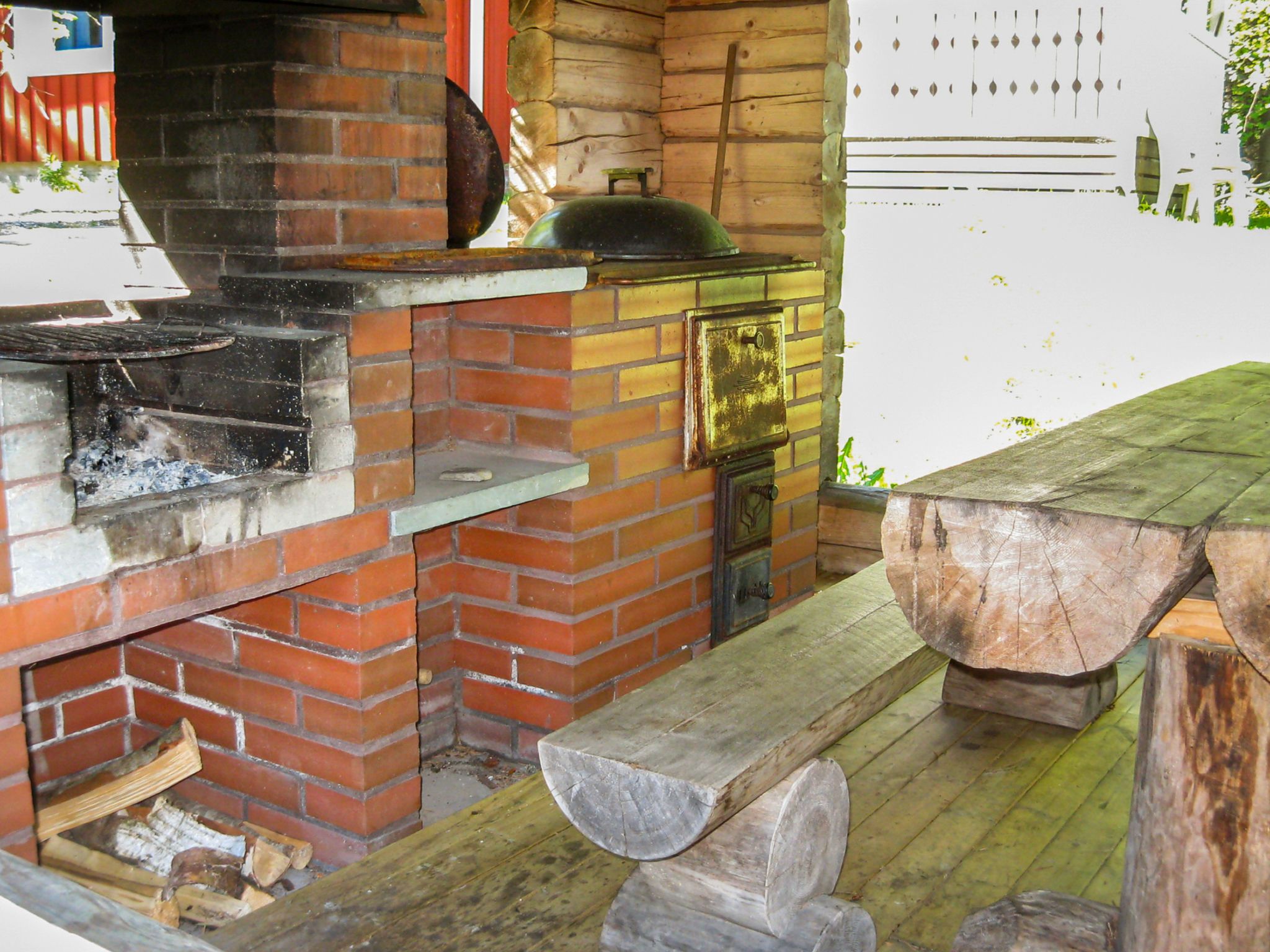 A brick-built outdoor cooking area with a grill and a wood-fired oven.