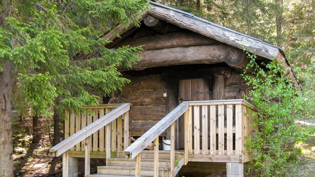A rustic cabin with a wooden staircase leading to a porch.