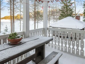 A snow-covered outdoor area with a wooden bench and a potted plant. - Koivupirtti by Interhome (Juuka)