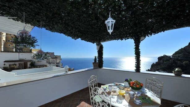 A terrace with a table set for dining, overlooking a coastal view. - Casa Carola beautiful sea view and relax !!!! (Positano)