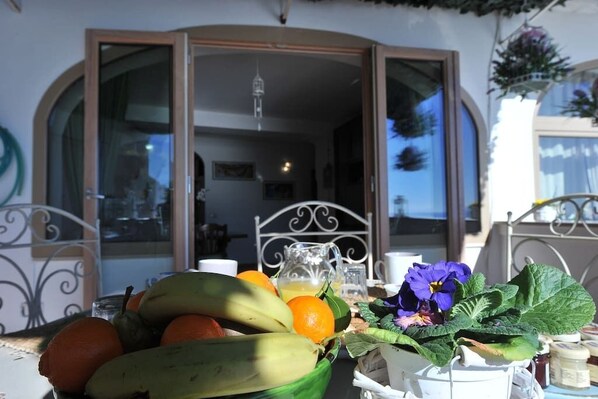 A table with fruits, a pitcher, and a flower arrangement.
