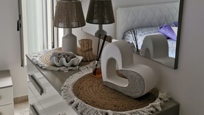 A modern bedroom with a large mirror, a white dresser with drawers, a round rug, and a bed with a tufted headboard. - Casa Carola beautiful sea view and relax !!!! (Positano)