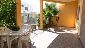 A patio with a table and chairs, a small palm tree, and a gate. - TORRE LAPILLO P. LAND 2 APARTMENTS 100 MT FROM THE SEA, ON THE MAIN COURSE (Torre Lapillo)