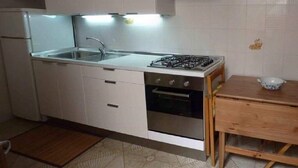 A modern kitchen with white cabinets, a stainless steel stove, and a wooden table. - TORRE LAPILLO P. LAND 2 APARTMENTS 100 MT FROM THE SEA, ON THE MAIN COURSE (Torre Lapillo)