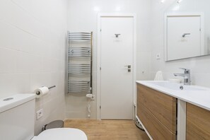 Une salle de bain moderne équipée d’un WC, d’un lavabo, d’un miroir et d’un porte-serviettes.
