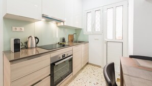 A compact kitchen with a built-in oven, a kettle, and a coffee maker on the countertop. - Fresh and Clean apt for 6 in Koukaki (Athens)
