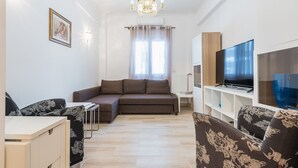 A modern living room with a sofa, a TV, and a chandelier. - Fresh and Clean apt for 6 in Koukaki (Athens)