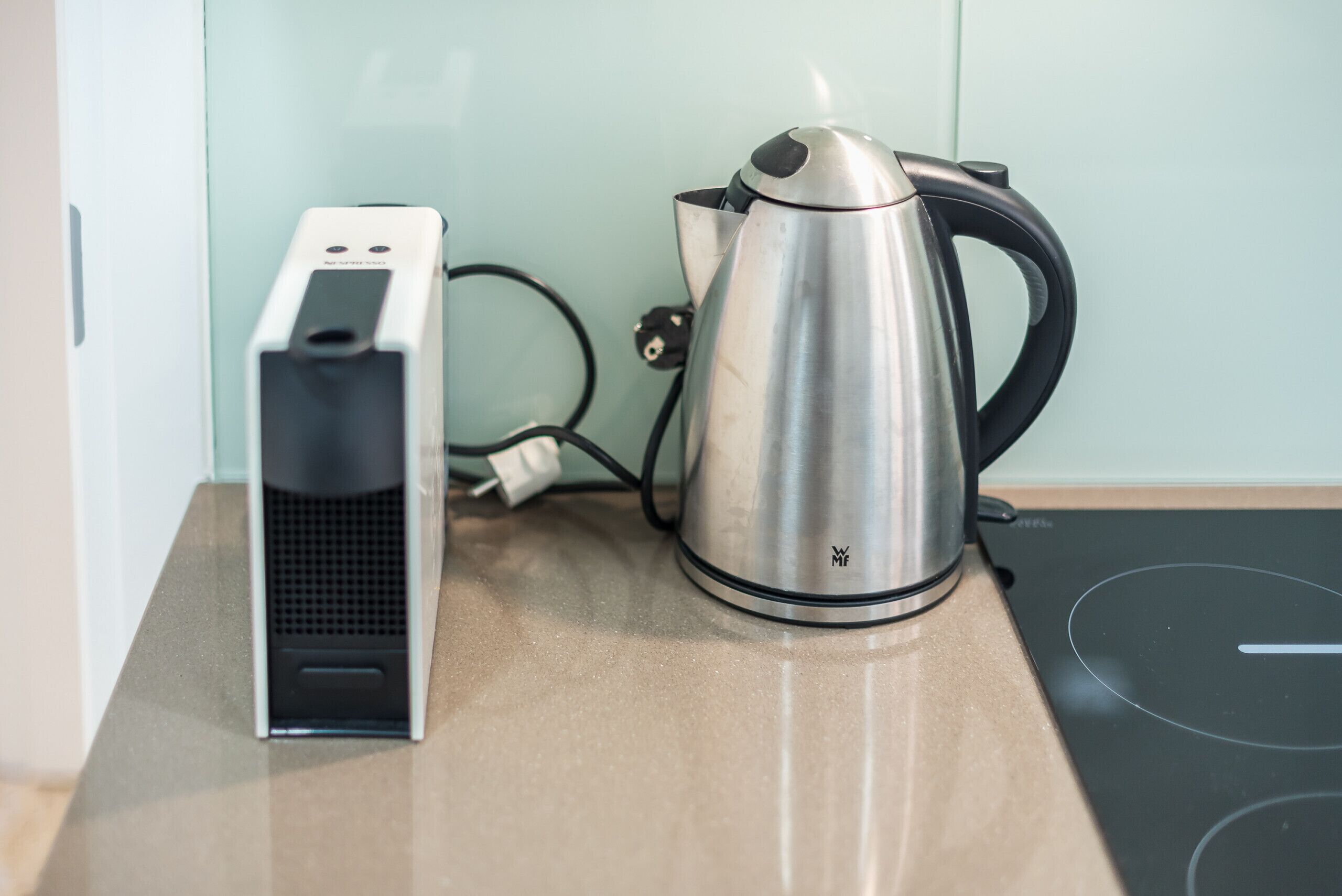 Een keuken met een waterkoker en koffiezetapparaat op een aanrecht.