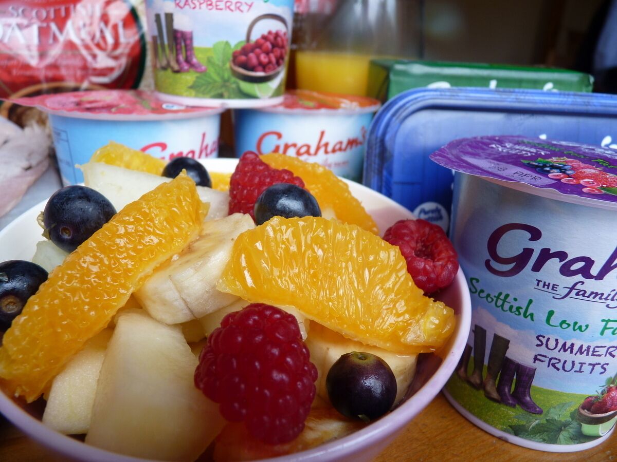 A bowl of mixed fruits including bananas, oranges, blueberries, and raspberries.
