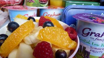 A bowl of mixed fruits including bananas, oranges, blueberries, and raspberries.