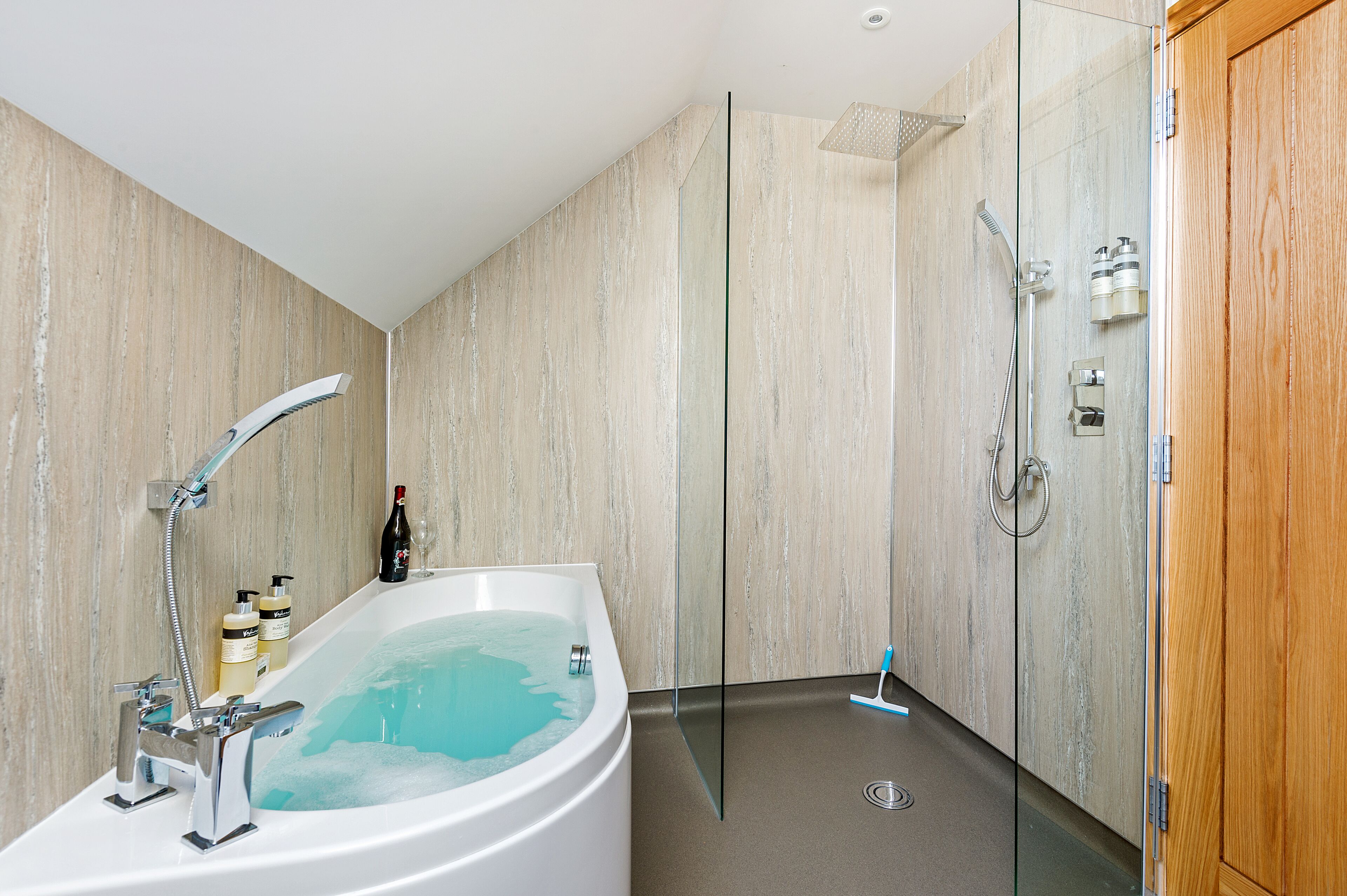 Un baño moderno con una bañera independiente, una ducha con cerramiento de vidrio y una puerta de madera.