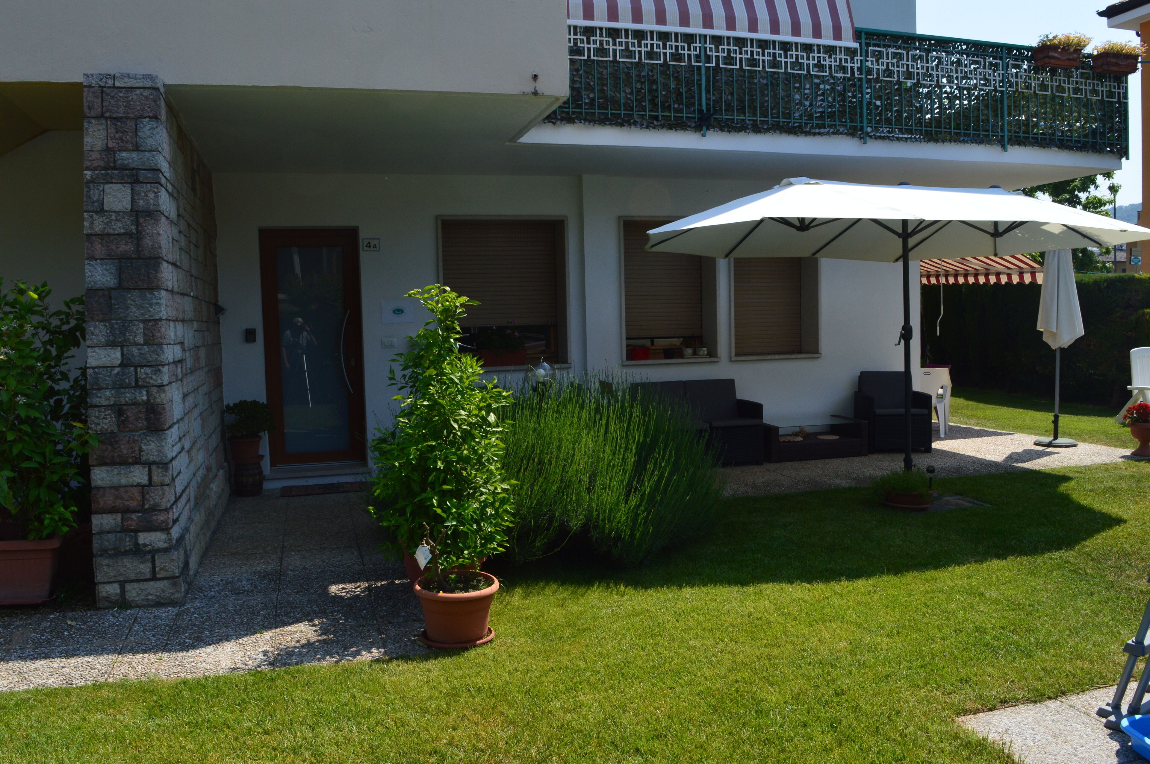 A two-story building with a balcony, a covered outdoor seating area, and a well-maintained lawn.