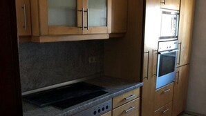 Eine Küche mit Holzausstattung, einem eingebauten Backofen und einem Kochfeld.