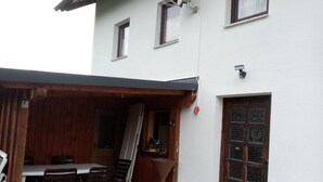 Eine Terrasse mit Tisch und Stühlen, einem großen Pflanzgefäß und einer Tür mit einer Schmetterlingsverzierung.