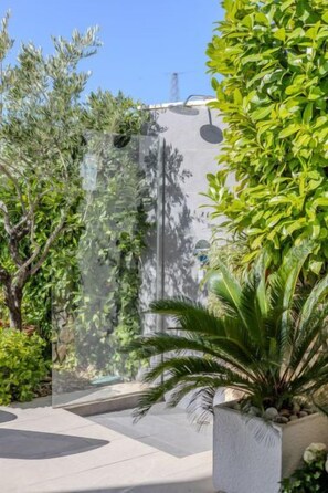 A modern outdoor area with a glass wall, various plants, and a concrete floor. - Vacation home Luka by Interhome (Makarska)