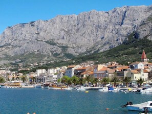 A coastal town with buildings, a marina, and a mountain backdrop.