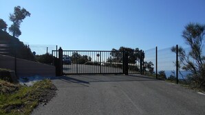 A gated entrance with a metal gate, a paved path, and a fence.