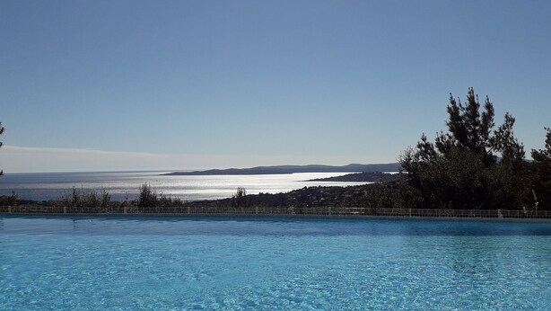 A clear blue pool with a view of the sea and distant hills.