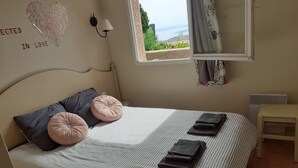 A neatly made bed with striped bedding, two pink decorative pillows, and three folded towels.