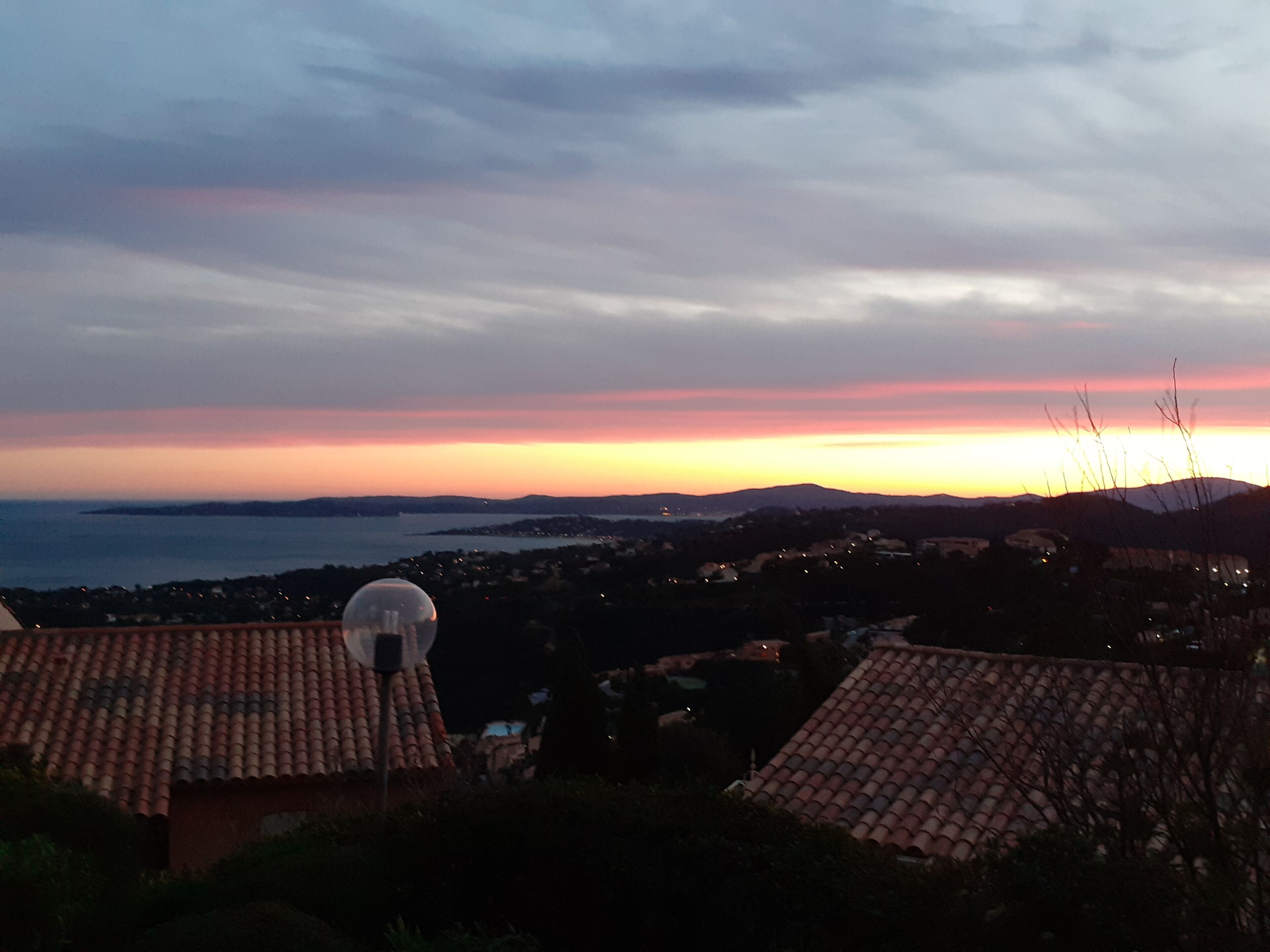 A coastal sunset view with a weather station in the foreground.