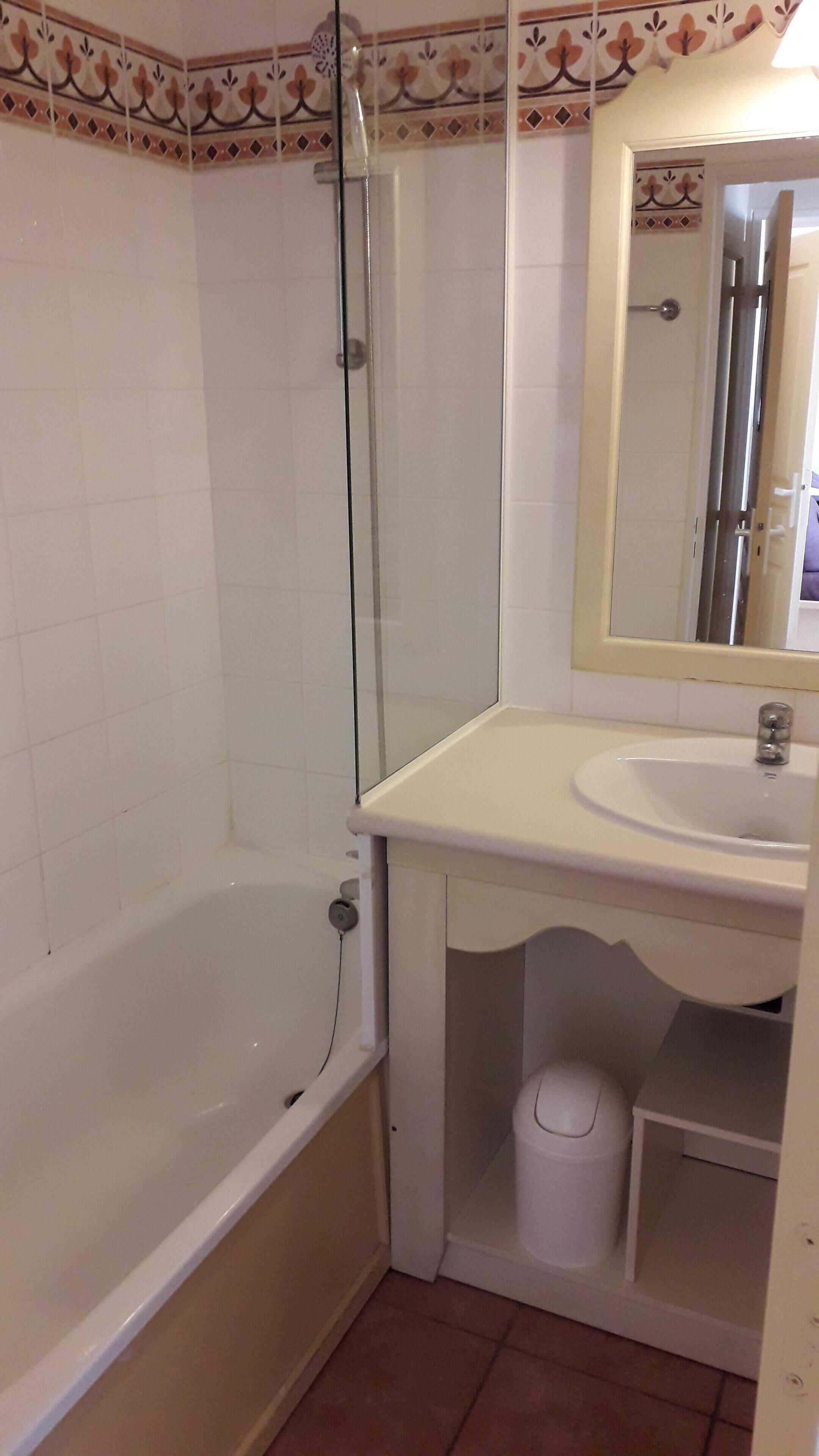 A bathroom with a bathtub, a glass shower enclosure, a sink, and a mirror.