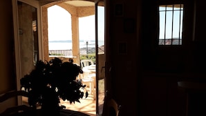 An open doorway leading to a balcony with a view of the sea.