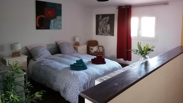 Una camera da letto con un letto, comodini, un paralume e tende alla finestra.