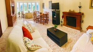 Una sala de estar con sofá, mesa de centro, chimenea, televisor y comedor.