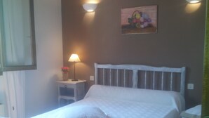 Een slaapkamer met een houten bed, een nachtkastje met een lamp en een schilderij aan de muur.