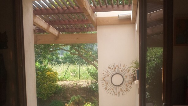 Een open terras met een houten tafel, stoelen en potplanten.