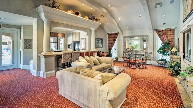 A spacious living room with a red patterned carpet, a beige sofa, a coffee table, and a dining area with a chandelier. - "Scottsdale Gem Near Pickleball Courts & Park!" (Scottsdale)