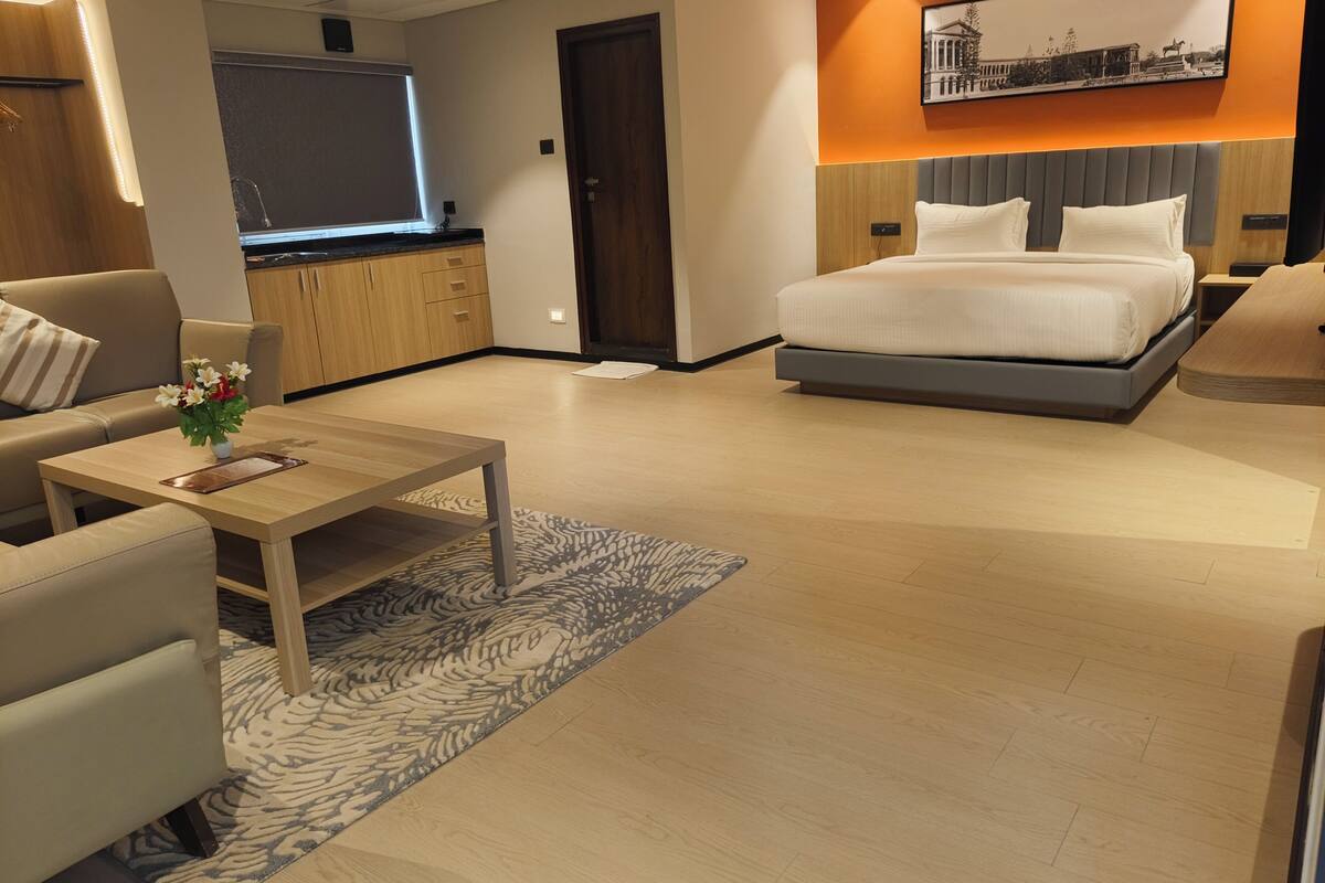 Una habitación de hotel moderna con una cama, un sofá, una mesa de centro y un televisor.