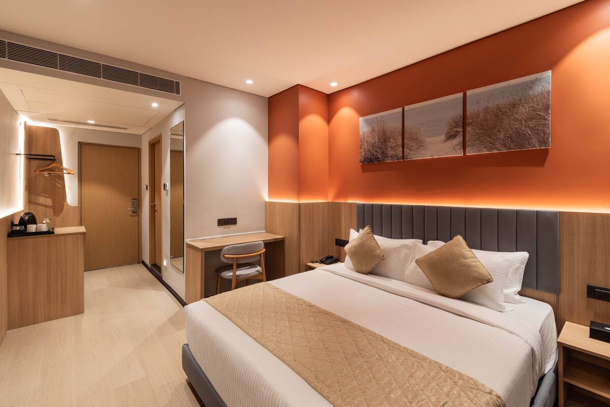 Una habitación de hotel moderna con una cama grande, un escritorio, una silla y un espejo.