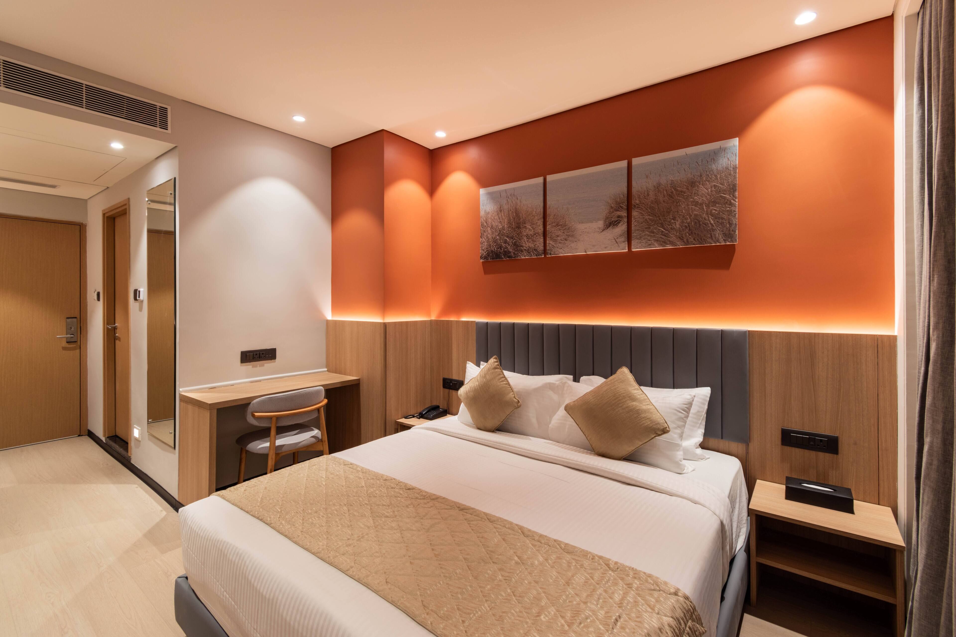 Una habitación de hotel moderna con una cama grande, un escritorio, una silla y un espejo.