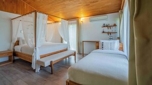 A bedroom with a wooden ceiling, two beds with white bedding, a bedside table, and a small table with decorative items.