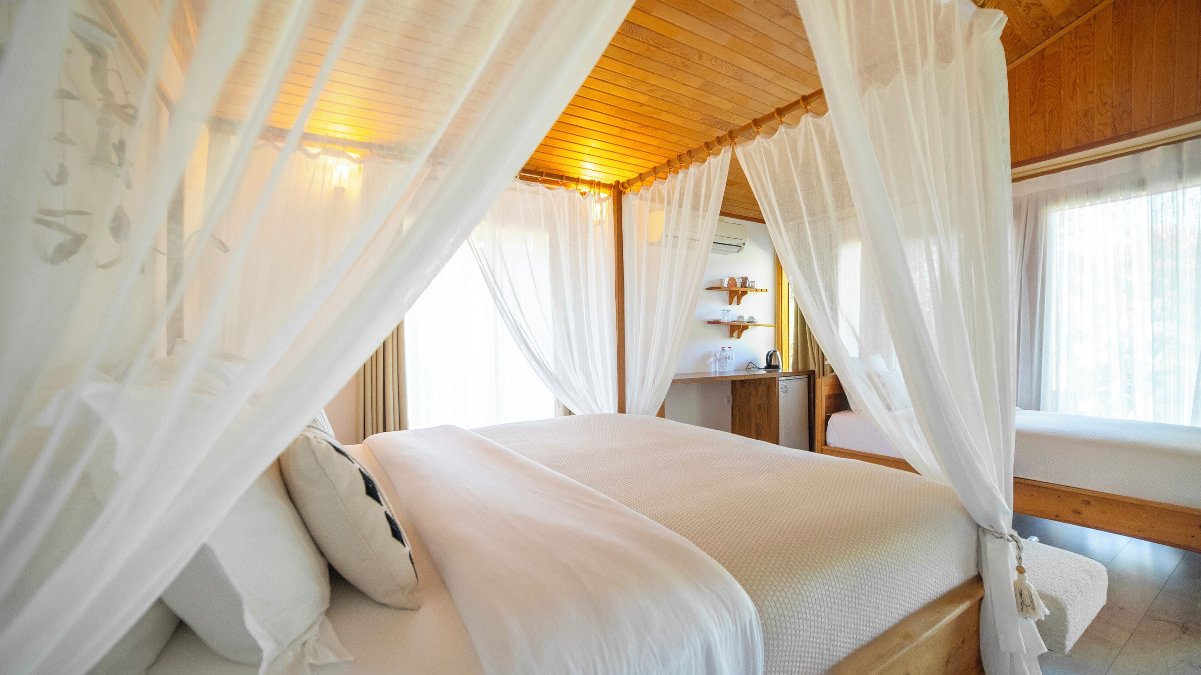 Une chambre à coucher avec un lit à baldaquin, un plafond en bois et une petite table de chevet sur laquelle se trouve une bouilloire.
