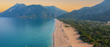 A coastal beach with mountains in the background.