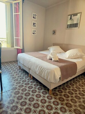 Une chambre à coucher avec un lit, une fenêtre avec des rideaux et un sol à motifs.