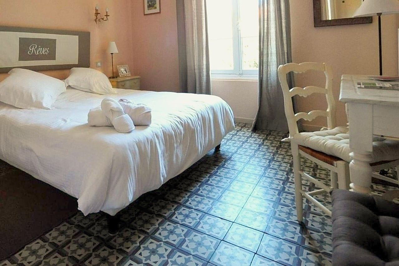 Ein Hotelzimmer mit Bett, Stuhl, Schreibtisch und einem Fenster mit Vorhängen.