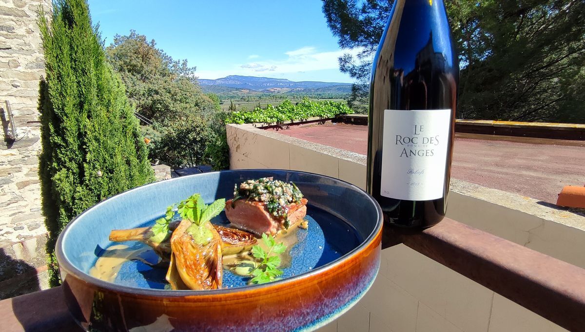Una mesa de comedor con un plato de comida y una botella de vino en un balcón con vistas panorámicas.