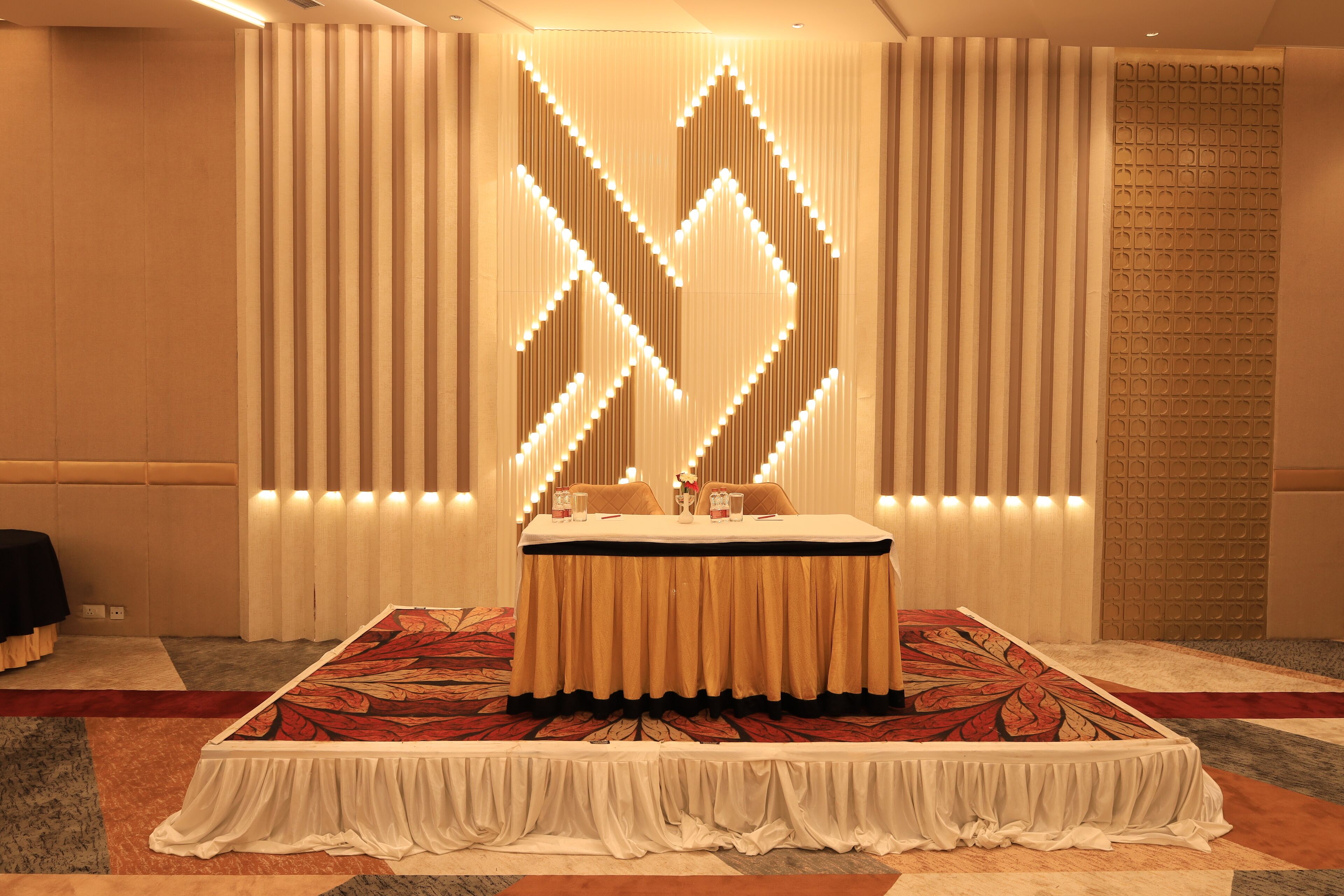 Une chambre d’hôtel avec un grand lit, un mur décoratif orné de panneaux verticaux et une moquette à motifs.